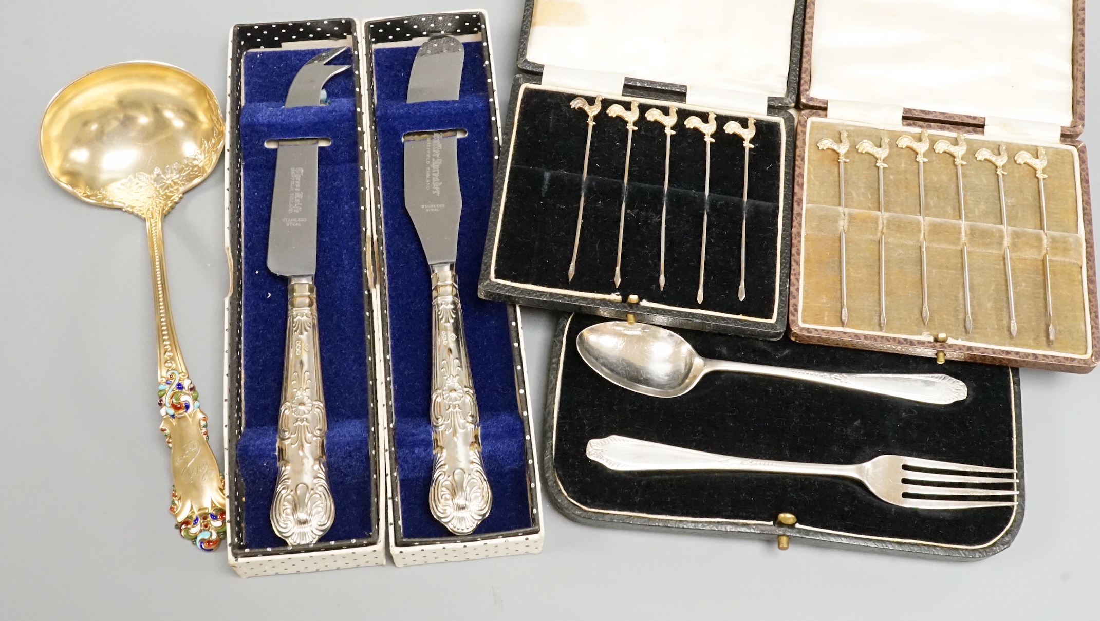 Three cased sets including silver cocktail sticks, two boxed bread knives and a sterling ladle.
